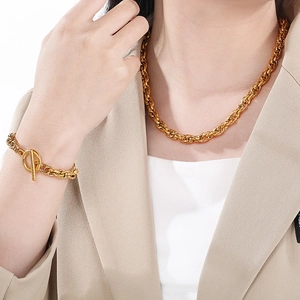 Detail of golden twist chain necklace and toggle clasp bracelet on a model
