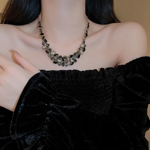 Detail of luxury teardrop tassel necklace with black and dark green gemstones on a model