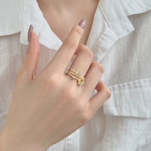 Detailed view of a gold-plated butterfly ring with sparkling cubic zirconia on a finger
