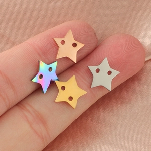 Polished stainless steel star charms in gold and silver held on fingertips for size comparison