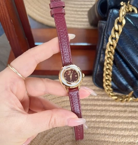 Close-up of elegant women's watch with burgundy leather strap and golden round case