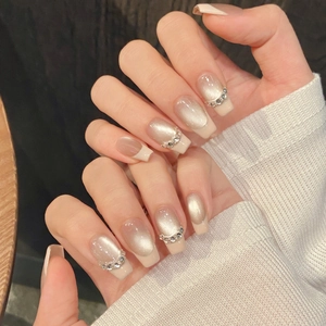 Détail d'ongles press-on œil-de-chat champagne avec des accents de strass brillants