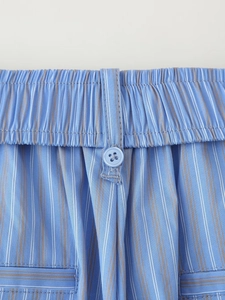 Detail of blue striped pajama pants featuring elastic waistband and button fly closure