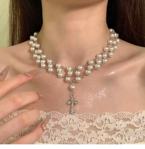 Close-up of double layer pearl choker necklace with a crystal-encrusted cross pendant