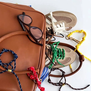 Platte weergave van kleurrijke gevlochten touwen, leren tas en sneakers voor accessoires