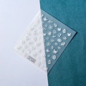 Detailed macro view of 5D white floral embossed nail stickers and butterfly designs