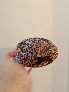 Detailweergave van de luipaard baret met suède textuur en een donkerbruine strik als accent