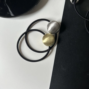Elastic hair ties with brushed gold and silver heart-shaped alloy beads on leather background