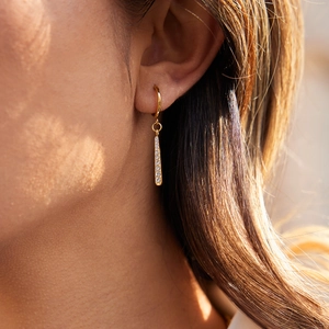 Gros plan de boucles d'oreilles pendantes en acier titane doré avec zircons blancs