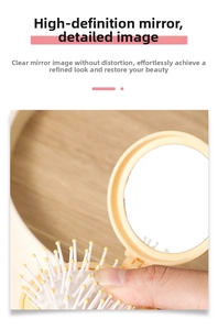 Detail of a portable mini folding hairbrush with a clear integrated mirror and massage pins
