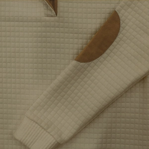 Dettaglio della maglia a nido d'ape beige con motivo trapuntato a quadri e toppa sul gomito