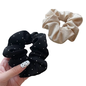 Set of black and beige ribbed fabric scrunchies with silver rhinestones on white background