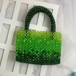 Detail of handmade green gradient acrylic beaded handbag on a decorative white background