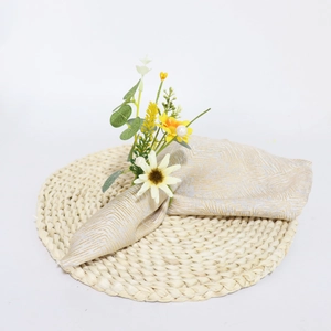 Detail of daisy napkin ring with pearls and patterned napkin on a woven mat