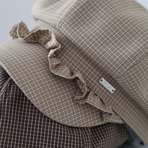 Detail shot of the ruffled edge and plaid fabric texture on a cotton baker boy cap