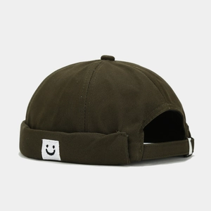 Detail of square smiley face patch on olive green Miki hat with metal buckle strap