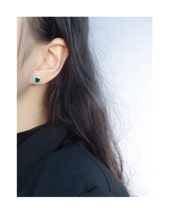 Detail of heart-shaped green crystal stud earrings with pavé zircons on ear