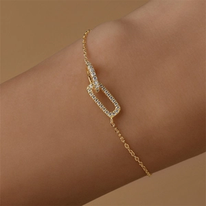 Close-up of interlocking geometric gold link bracelet with micro-paved sparkling crystals