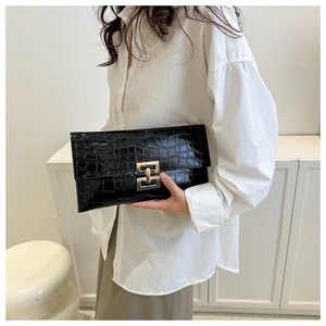 Detail of black crocodile pattern clutch bag featuring a gold rectangular metal buckle