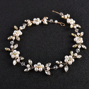 Detailed view of bridal headpiece featuring gold wire, white pearls, and crystals