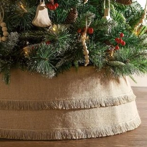 Detail of grey knitted Christmas tree skirt with festive tassel fringe and tree base