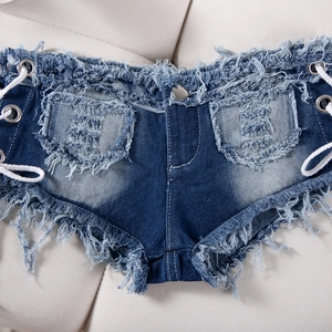 Dettaglio degli shorts in denim blu scuro con bordi sfrangiati e lacci decorativi laterali
