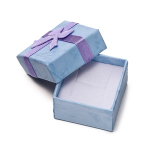 Detail of light blue textured paper jewelry box with purple ribbon bow and inner padding