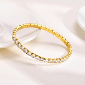 Close-up of golden tennis bracelet featuring square-cut zircons on a white ceramic surface