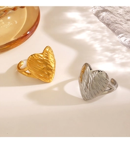 Detail of 18K gold and silver heart rings with textured surface in warm natural light