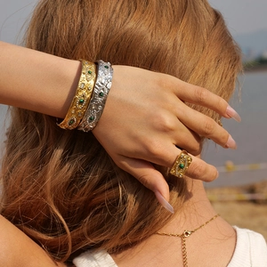 Chunky gold and silver lava texture bracelets and rings set with malachite on beach background