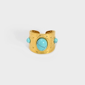Detailed view of the bohemian gold cuff with embossed patterns and turquoise stones