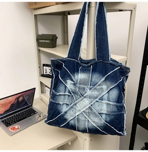 Detailed close-up of X-shaped patchwork denim and distressed frayed edges on the tote bag