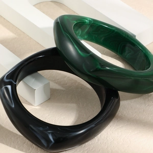 Detail view of luxurious emerald green and black marble resin bracelets on stone blocks