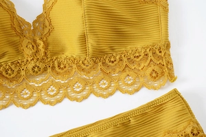 Detailed close-up of mustard yellow lace bra and striped fabric showing fine textures