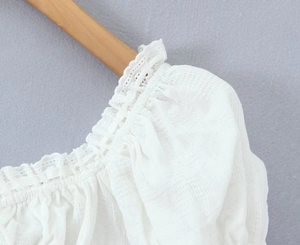 Gros plan sur le col en dentelle blanche et la texture du tissu de ce haut femme