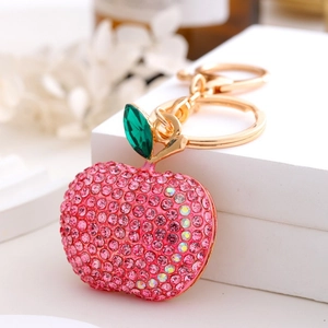 Close-up of pink rhinestone apple keychain with gold chain and green leaf charm
