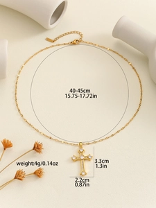 Detail view of a gold cross pendant necklace with sparkling cubic zirconia on a beige base