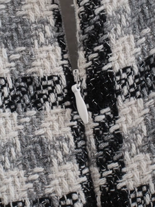 Dettaglio macro del tessuto tweed a quadri con filo metallico argento e zip invisibile