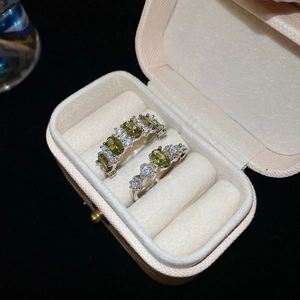 Close-up of vintage silver rings with oval green gems set in a luxury jewelry box