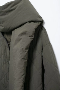 Detail of diamond quilted texture and hood on dark olive green casual winter jacket