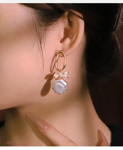 Detail of model wearing vintage baroque pearl drop earrings with matte gold trim