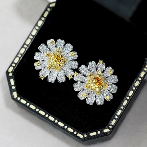 Macro shot of daisy earrings with golden center and silver petals on black velvet