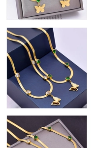 Macro shot of gold snake chain necklace with green heart gems and butterfly pendant