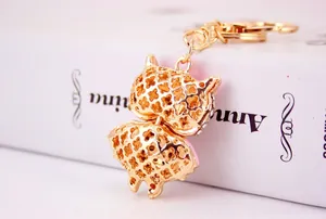 Macro view of gold hollow-out owl keychain with pink lining on white book spine
