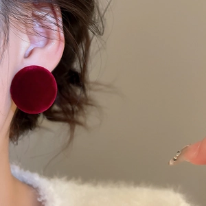 Side view of a model wearing red velvet round button earrings with a vintage texture