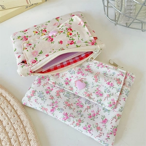 Détail de pochettes en toile fleurie avec boutons cœur et poches avant sur bureau blanc