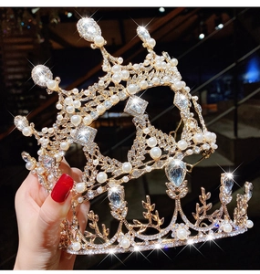 Detailed view of hand-held gold princess crown with white pearls and sparkling crystals