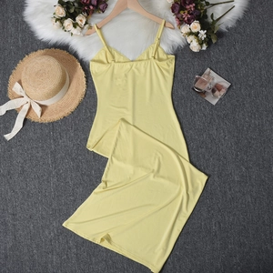 Abito estivo giallo a spalline sottili con accessori per le vacanze su superficie ruvida