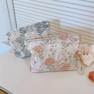 Macro detail of blue and coral dandelion floral jacquard pouches with metal zippers