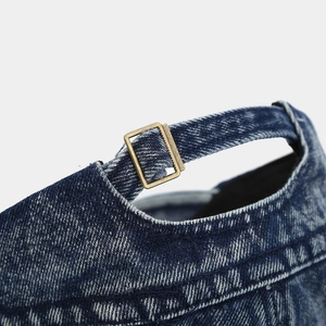 Detail of washed denim cap showing adjustable metal buckle and vintage bronze hardware